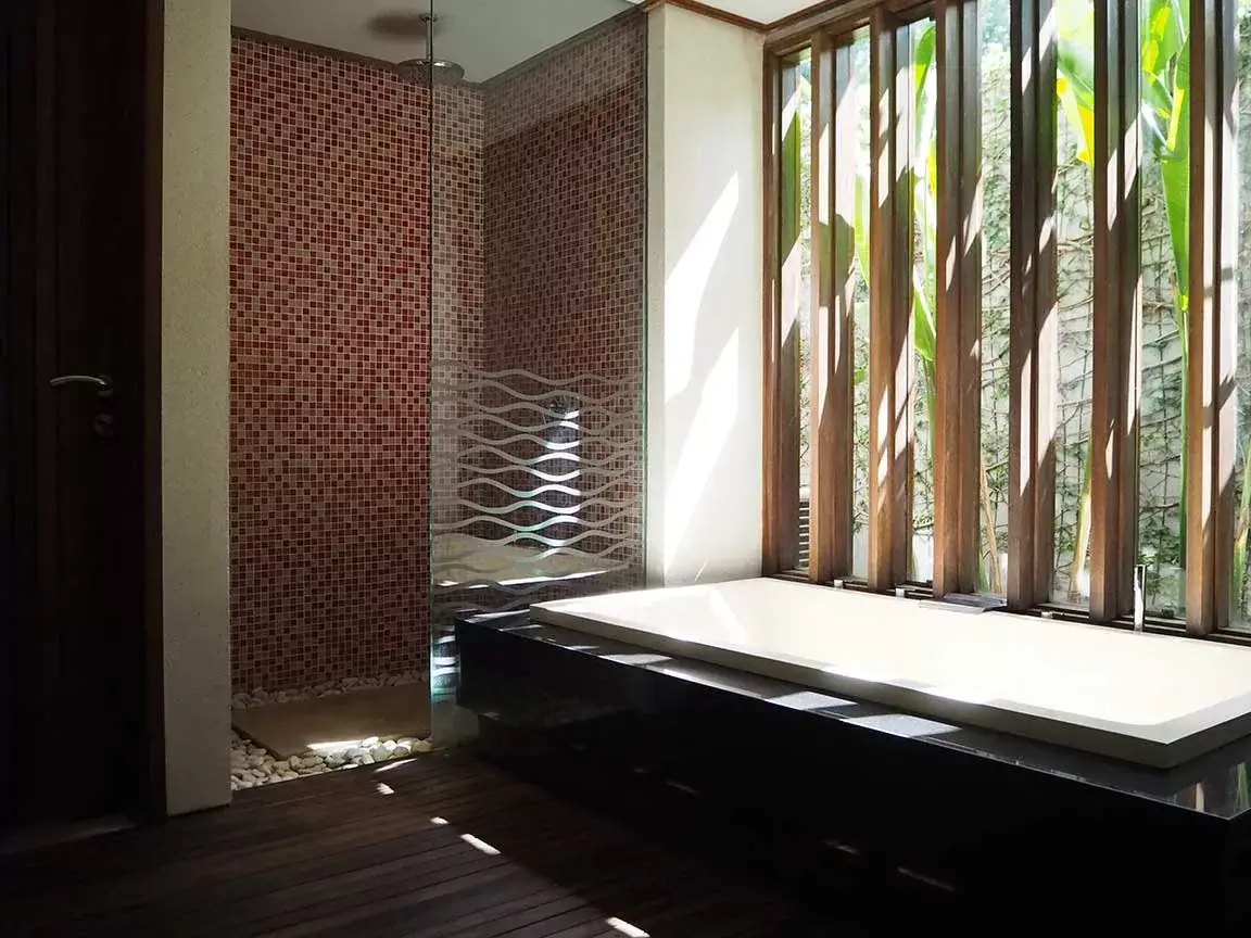 Bathtub and shower area with patterned stone walls