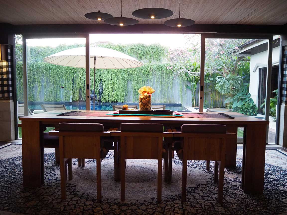 Dining table beside full-height garden windows